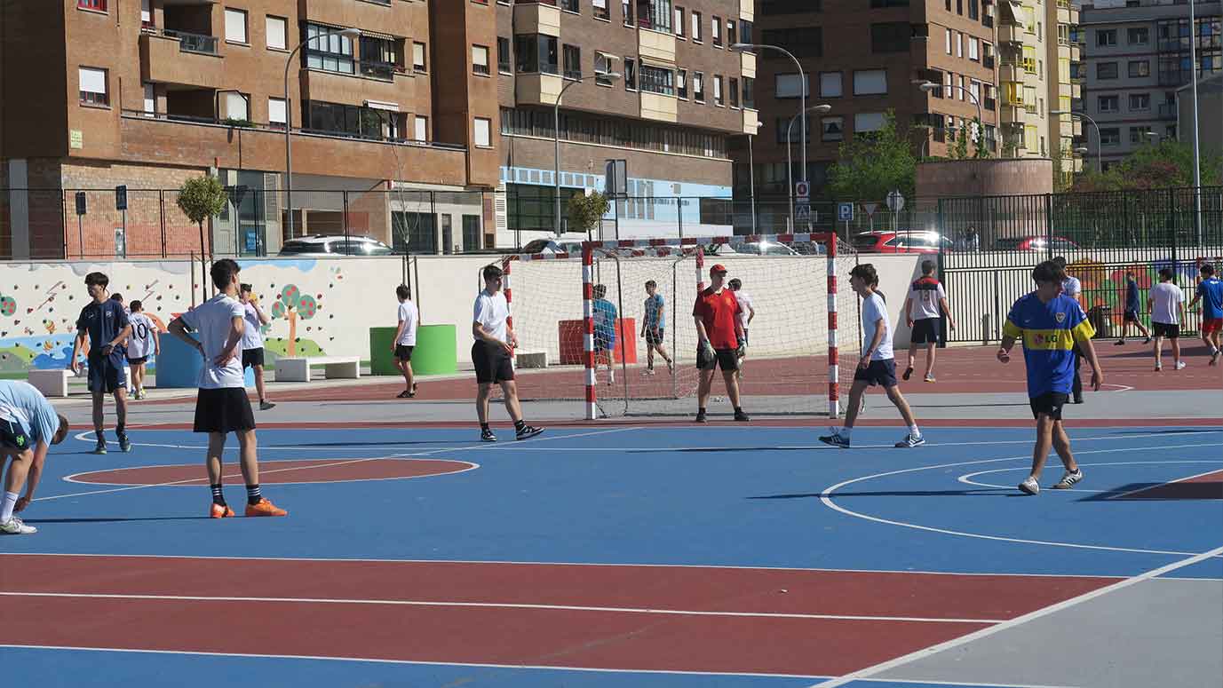 estudiantes jugando al fútbol en una cancha al aire libre