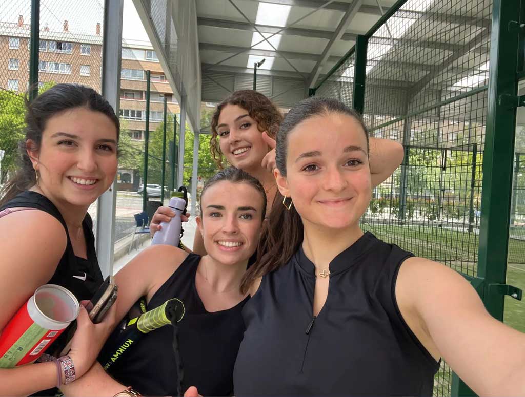 chicas sonriendo frente a unas pistas de pádel