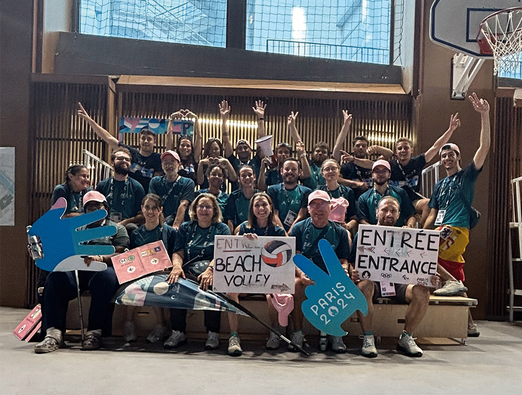 grupo de voluntarios durante los juegos olímpicos posando frente al estadio