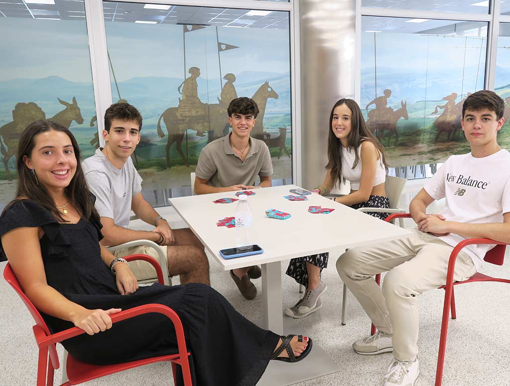 chicos y chicas jugando a las cartas en el comedor del colegio mayor