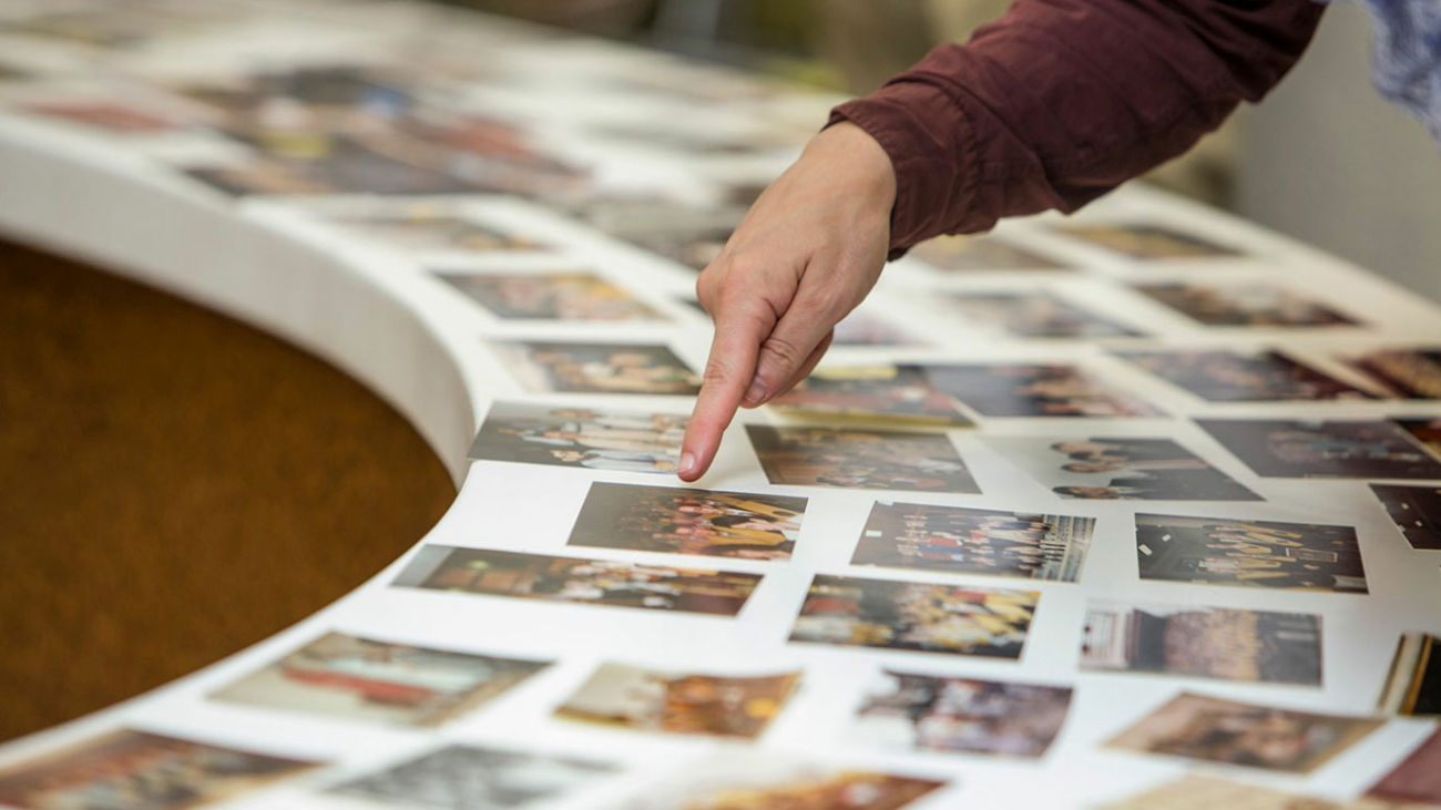 mano de un antiguo alumno apuntando hacia una fotografía de recuerdo del colegio mayor